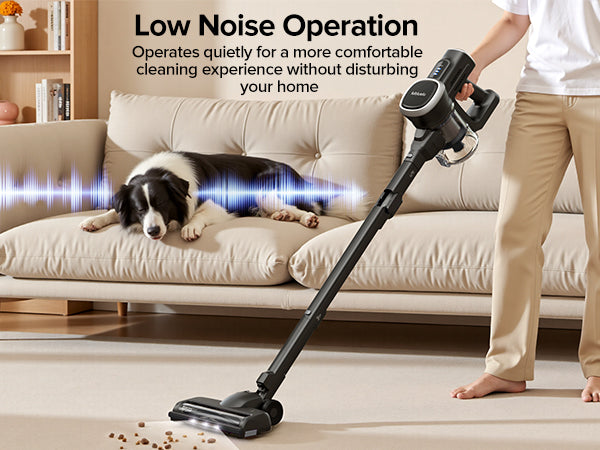 Person using a vacuum cleaner on a carpet with a dog resting on a couch, emphasizing low noise operation.