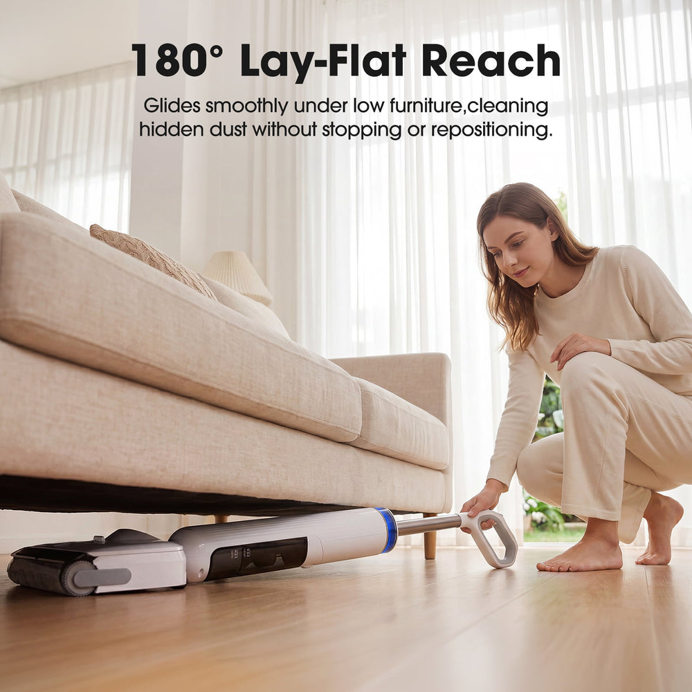 Woman using a vacuum cleaner with '180° Lay-Flat Reach' feature under a couch.