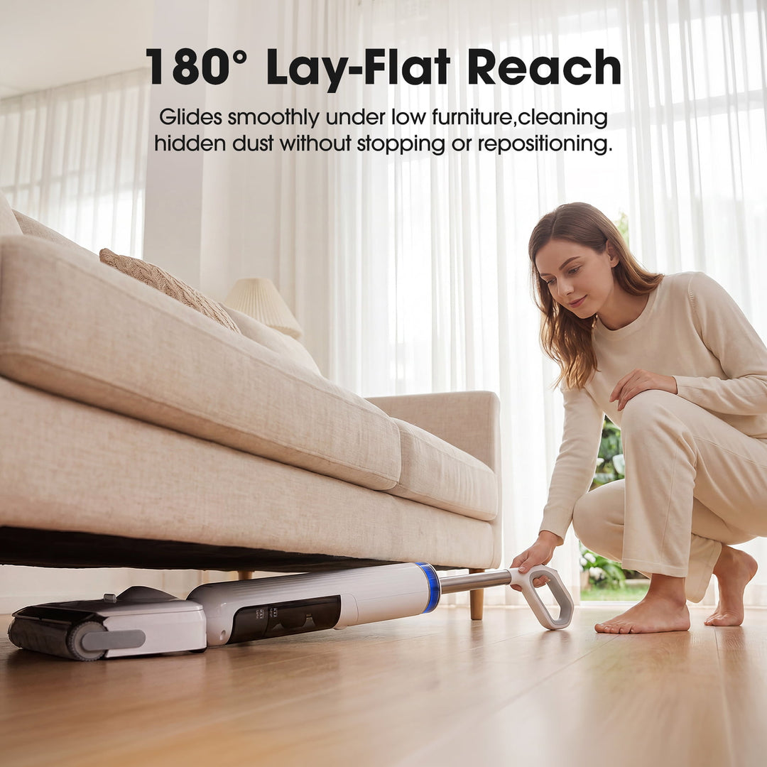 Woman using a vacuum cleaner with '180° Lay-Flat Reach' feature under a couch.