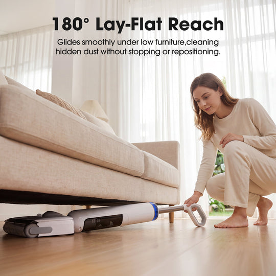 Woman using a vacuum cleaner with '180° Lay-Flat Reach' feature under a couch.