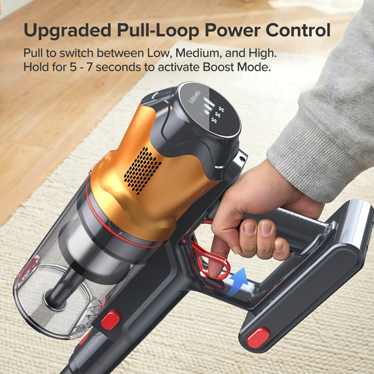 Hand holding a handheld vacuum cleaner with power control features on a wooden floor.